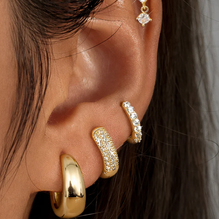 Elegant Mini Huggies Earrings set in gold worn in ears, showcasing modern jewelry design and sparkle.